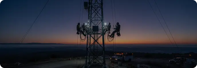 Engineers working on a telecommunications mast at dusk